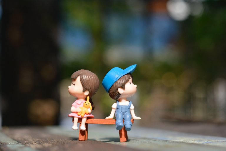 Zwei Spielfiguren, ein Junge und ein Mädchen, stehen mit dem Rücken zueinander. 