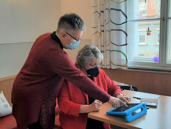 Kursleiterin zeigt Seniorin etwas am Tablet
