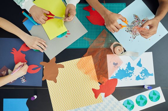 Kinderhände schneiden aus Papier Motive aus